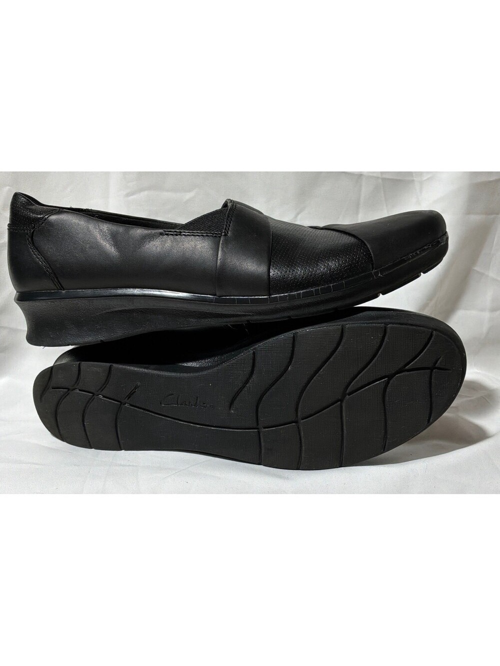 Clarks black leather slip-on shoes featuring a stylish pleated crossover design